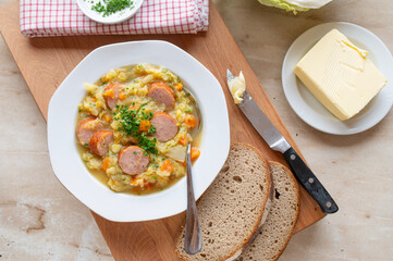 Traditional german savoy potato stew with sausage on plate und rustic background