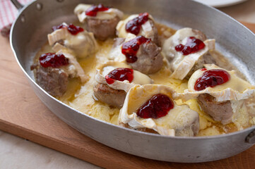 Baked pork tenderloin with camembert and cranberries in a baking dish fresh and homemade cooked