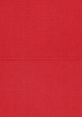 A close-up view of a red cardboard envelope with a visible horizontal fold crease. The surface shows a matte paper texture with subtle fibers.