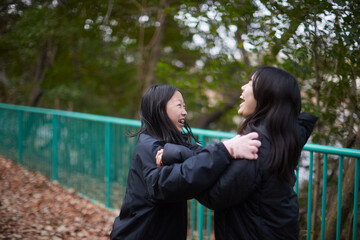 冬の朝の公園で楽しく散歩しながら遊んでいる女子中学生姉妹の姿