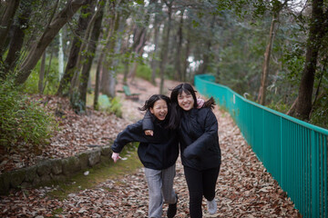 冬の朝の公園で楽しく散歩しながら遊んでいる女子中学生姉妹の姿