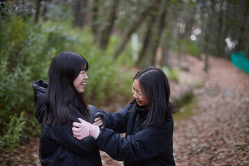冬の朝の公園で楽しく散歩しながら遊んでいる女子中学生姉妹の姿