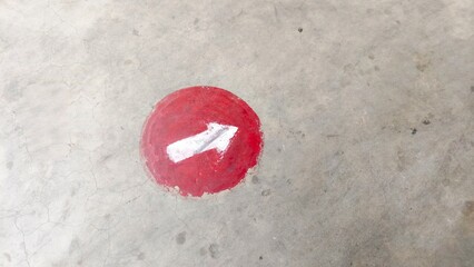 Red direction arrow painted on concrete floor, ideal for navigation signs, safety guidance, urban design, and editorial use. Perfect for buyers in transportation, public facilities, education, and way