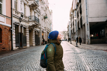 Vilnius, Lithuania. Young Beautiful Pretty Caucasian Girl Woman Dressed In Green Jacket And Blue Hat Enjoying Life And Smiling On Street Of Town.