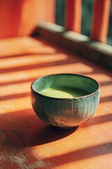 Close-up of green tea in a bowl on a weathered table with orange chair in sunlight