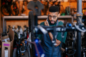 Mechanic talking on phone in bicycle repair shop