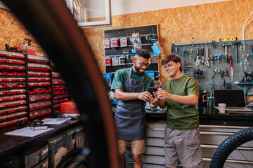 Workshop colleagues checking phone discussing bicycle repair service