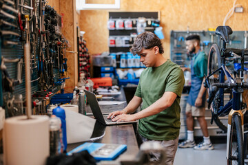 Mechanic using laptop managing bicycle repair service