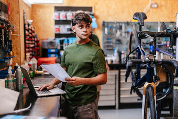 Mechanic managing bicycle repair shop finances and service orders