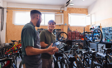 Mechanics discussing bicycle repair with digital tablet