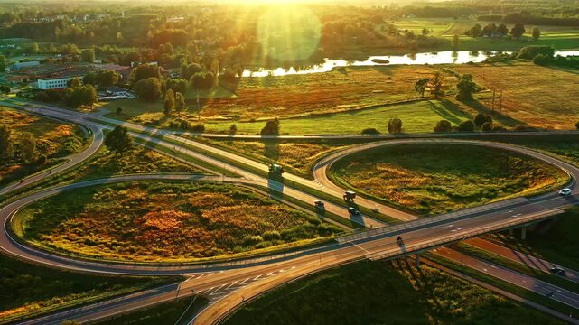 Symmetrical road interchange with curved loops in green rural area on golden hour sunlight