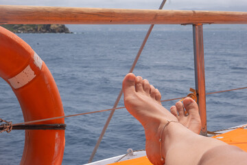 Relaxing on a boat with feet resting by the water near a resort during a sunny day at the sea