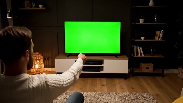 Man watching TV with a customizable greenscreen mockup for content insertion