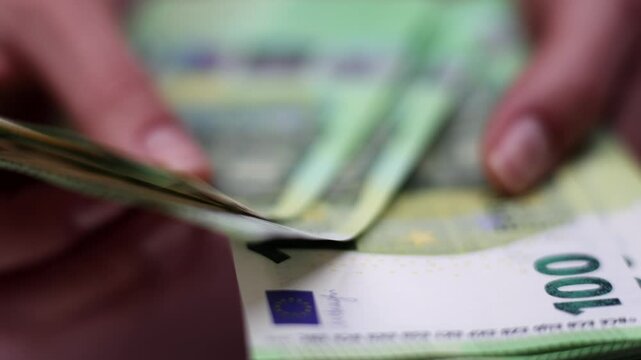Hands are counting and organizing a stack of euro banknotes, showcasing the detailed texture and design of the currency, emphasizing the action of handling money