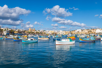 Colorful traditional fishing boats float in Marsaxlokk harbor, Malta.