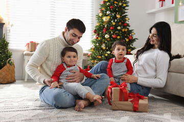 Fototapeta premium Parents and their cute twin babies with Christmas gifts at home