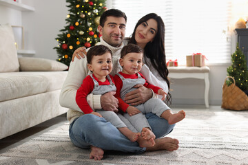 Fototapeta premium Parents and their cute twin babies at home. Christmas season