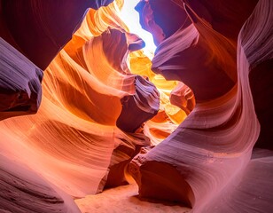 View of a carved sandstone canyon with light streaming from above. The walls are smooth, swirling, and various shades of red and orange