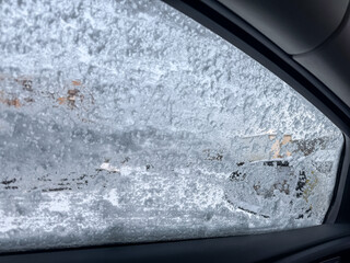 A car in the snow, snow crystals on a car in a severe frost. Winter landscape, frost. Car windows freezing during the winter season close-up. Snow Covered Car on the Street. Winter urban scene. 