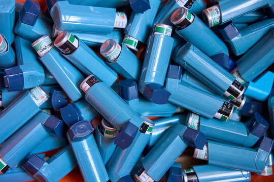 Blue salbutamol asthma inhalers piled together, medical respiratory treatment devices for emergency use indoors. Concept of asthma control, chronic disease management, and healthcare supply
