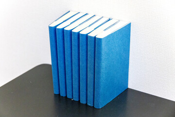 黒いテーブルに並べられた青い表紙の本