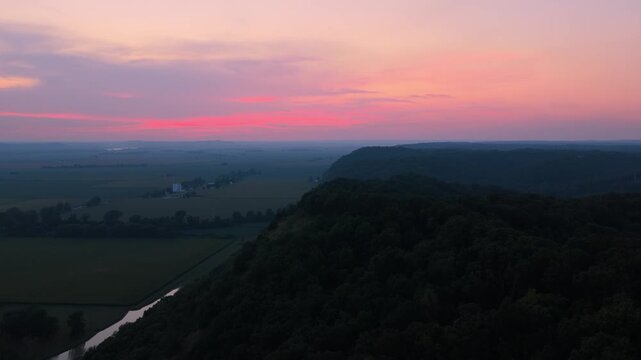 High Drone Shot Over The River Bluffs in Southern Illinois During Sunset. The colorful sky and rolling bluffs create an interesting contrast against the flat farmland below