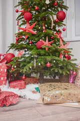 Decorated christmas tree with shiny red ornaments and festive wrapped gift boxes underneath