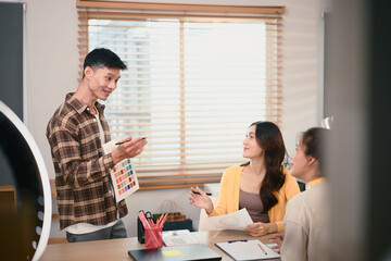 Fashion design team discussing clothing details and color selection at studio, reviewing samples and planning next collection together