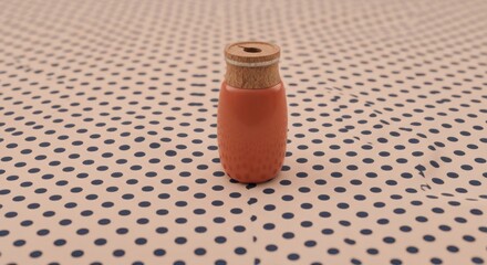 Ornate, terracotta-colored bottle with cork top on polka dot cloth