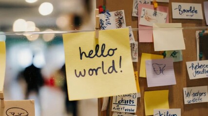 Hello World" sticky note on a board in a modern office environment