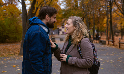 Fototapeta premium A smiling man and woman chat while standing together in a picturesque autumn park.