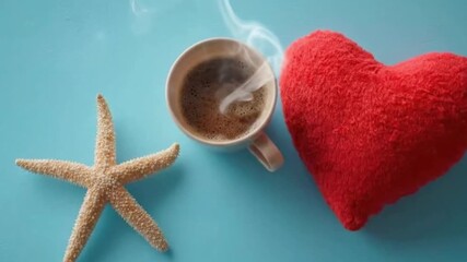 A serene top-down shot captures a cozy and inviting composition featuring a steaming cup of hot beverage, a soft red heart-shaped plush, and a natural starfish, all artfully arranged on a tranquil blu