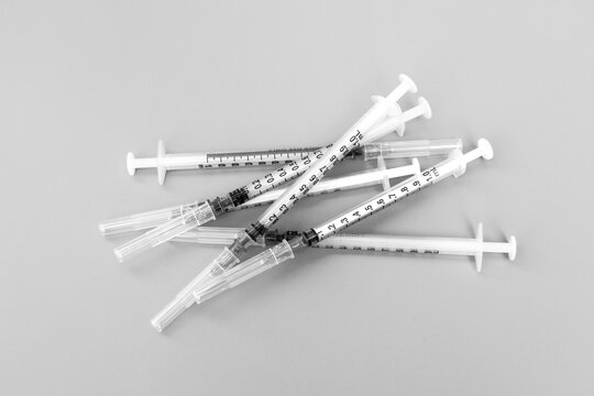 Medical equipment and infectious waste. A pile of used syringes with needles on a black and white background.