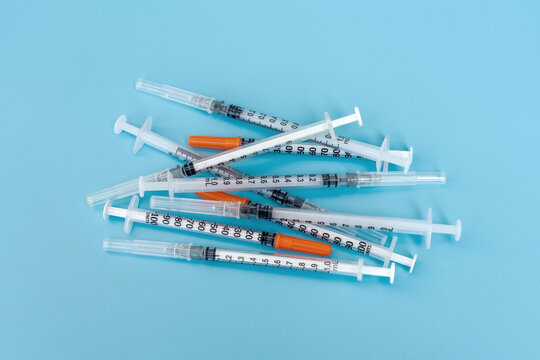 Medical equipment and infectious waste. A pile of used syringes with needles on a blue background.