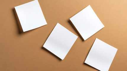 A minimalist composition featuring four blank white paper sheets arranged on a tan surface, conveying simplicity, potential, and space for creativity.  Neutral palette.