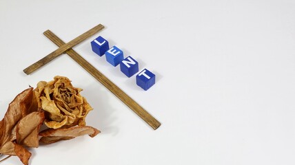 Christian cross with the inscription LENT, Lenten Holy Week, on wooden blocks against a dried rose...