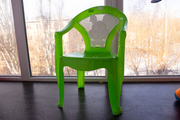Green Plastic Chair Indoors Near Window, Minimal Furniture