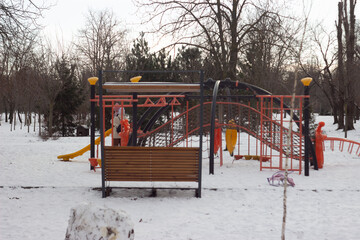 Playground with Slides and Benches in Snowy Park, Winter