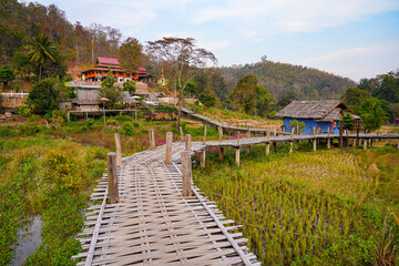 Fototapeta premium The winding Kho Ku So Bamboo Bridge stretching across dry rice paddies in Pai, Northern Thailand