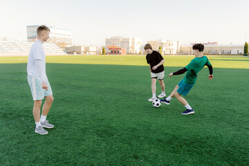 Three boys play soccer on a vibrant green field beneath a clear sky. Their laughter fills the air as they dribble and pass the ball, showcasing their skills in a friendly match.