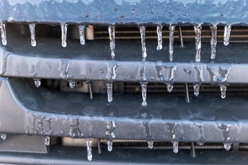 Winter frost creates stunning icicles on a car grille during a cold morning in a quiet neighborhood