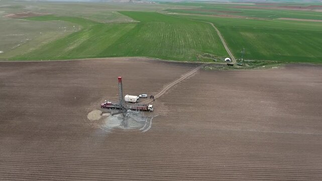 Aerial view of drilling rig extracting groundwater from alluvial flat plain. Artesian well and borehole operation bringing underground water to surface farmland