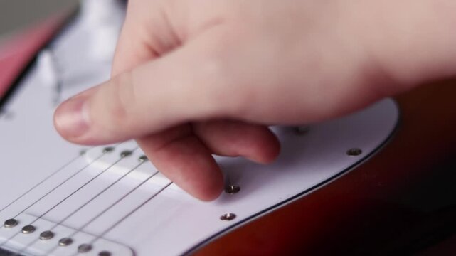 Close-up of a hand adjusting the volume knob on an electric guitar