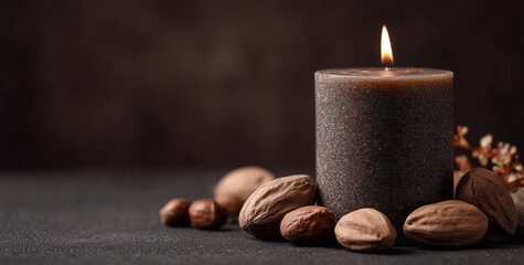 Warmly lit dark candle glowing amongst a collection of nuts including walnuts, hazelnuts, and pecans on a textured surface, evoking a cozy autumn or holiday ambiance