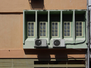 Brown exterior of a building with rectangular shape glass window frame and two split unit air conditioning box mounted on the wall.