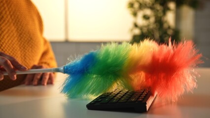 A vibrant rainbow duster sweeping over a black computer keyboard, representing cleaning and technology.