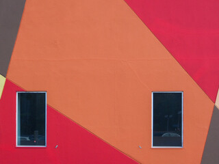 Two rectangular glass window on a geometrical pattern line groove with red and orange painted walls.