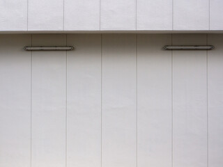 White wall with vertical parallel groove lines and wall mounted lighting