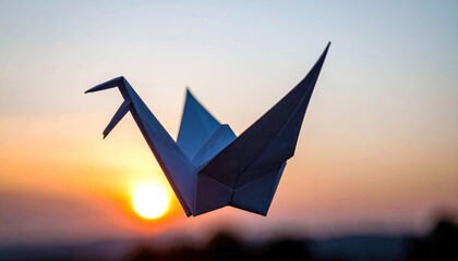 Paper crane soars against a vibrant sunset backdrop, symbolizing hope.