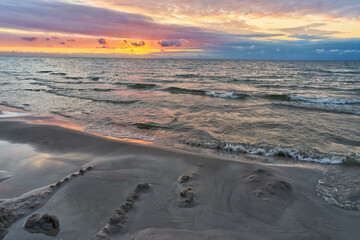 Beautiful landscape of sunset by baltic sea. Golden, shining sun going down and cloudy, colorful sky.	